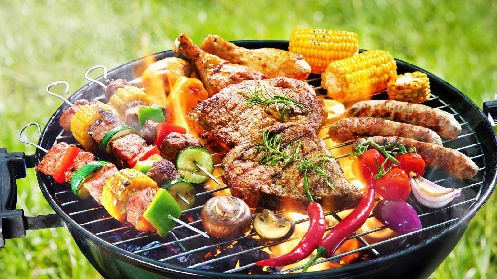 Grilled skewers, steaks, chicken, corn and vegetables on a BBQ grill